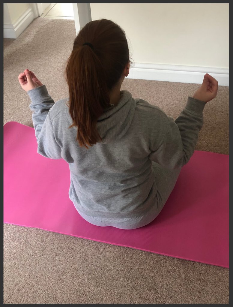Sitting yoga pose on a pink yoga matt